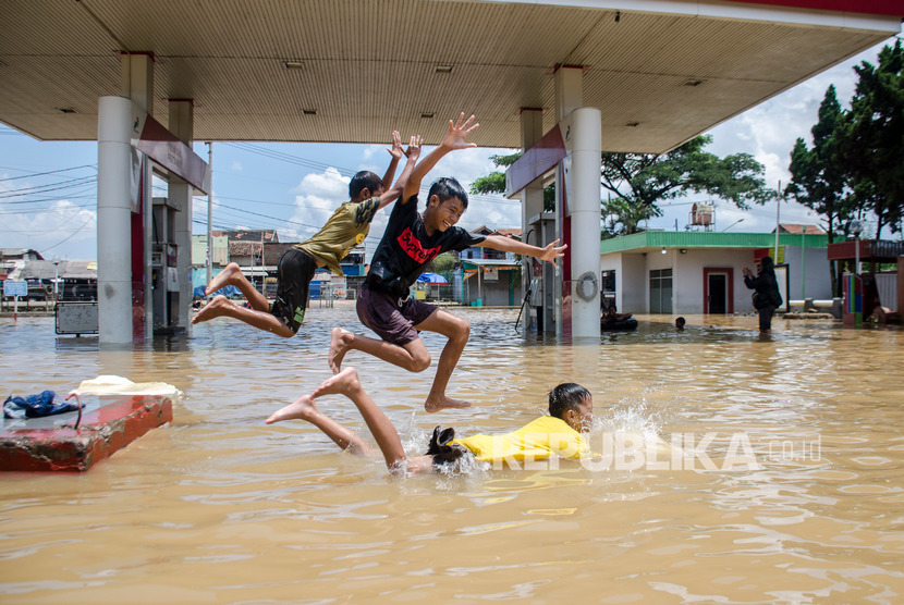 Sejumlah anak bermain di genangan banjir di Jalan Raya Baleendah, Kabupaten Bandung, Jawa Barat, Ahad (26/1/2020).