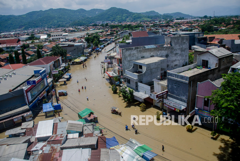 Warga melintas di genangan banjir di Jalan Raya Dayeuhkolot, Kabupaten Bandung, Jawa Barat, Ahad (26/1/2020).