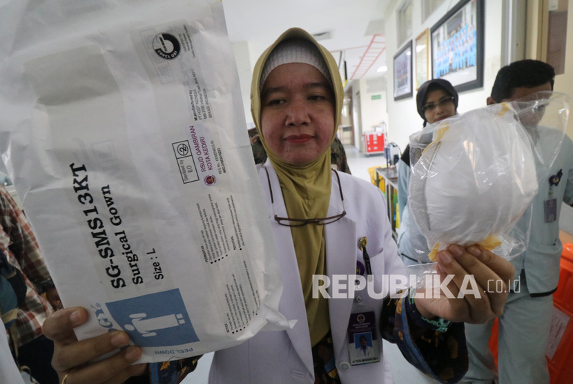 Seorang dokter memperlihatkan masker dan baju pelindung sekali pakai di ruang isolasi Rumah Sakit Umum Daerah (RSUD) Gambiran, Kota Kediri, Jawa Timur. Petugas Kemenkes lakukan uji petik virus Corona pada dua pasien TBC. Ilustrasi.