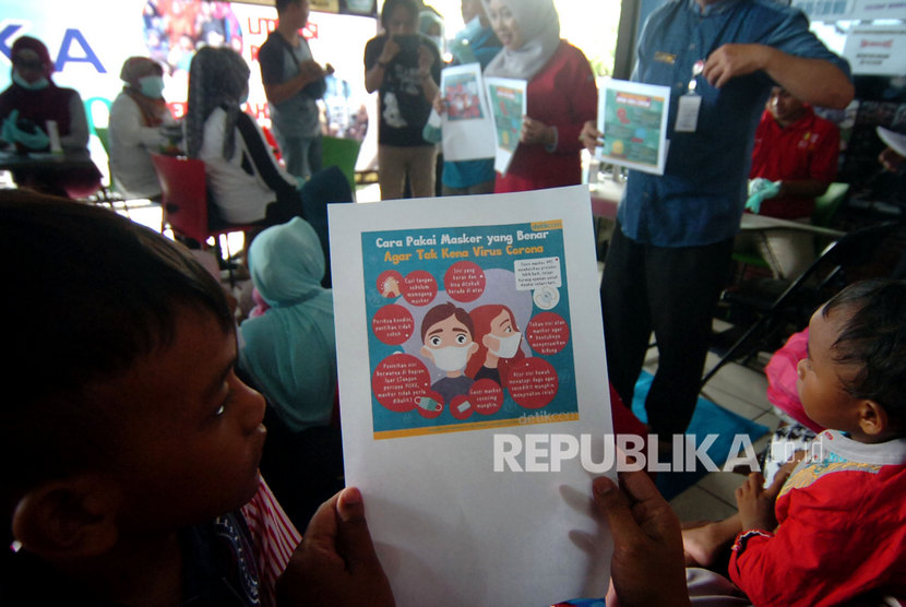 Seorang anak bersama orangtuanya membaca tentang bahaya dan penanganan wabah virus novel Coronavirus (nCoV) saat sosialisasi dan pengobatan gratis di sekolah terminal Sakila Kerti di Terminal Kota Tegal, Jawa Tengah, Jumat (31/1/2020).