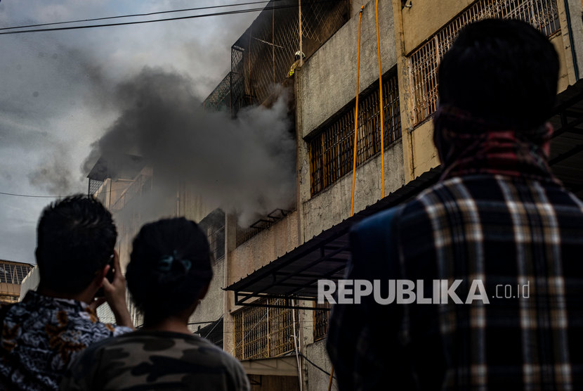 Warga menyaksikan kebakaran yang melanda kompleks ruko tekstil di kawasan Tanah Abang, Jakarta. 