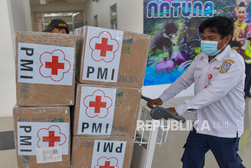 Petugas mendorong troli bermuatan kardus yang berisi masker bantuan dari PMI pusat yang baru tiba di Bandara Raden Sadjad, Ranai, Natuna, Kepulauan Riau, Selasa (4/2/2020).