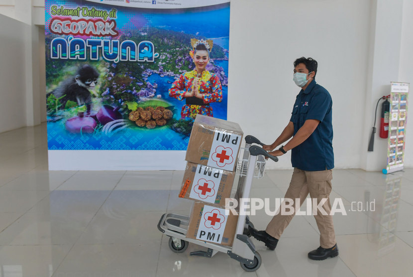 Petugas mendorong troli bermuatan kardus yang berisi masker bantuan dari PMI pusat yang baru tiba di Bandara Raden Sadjad, Ranai, Natuna, Kepulauan Riau, Selasa (4/2/2020). 