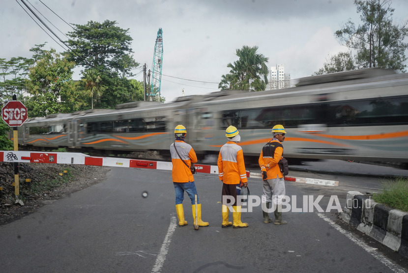Pekerja pembangunan flyover menunggu kereta api lewat di Palang Perlintasan Purwosari jalan Slamet Riyadi, Solo, Jawa Tengah, Rabu (5/2/2020)
