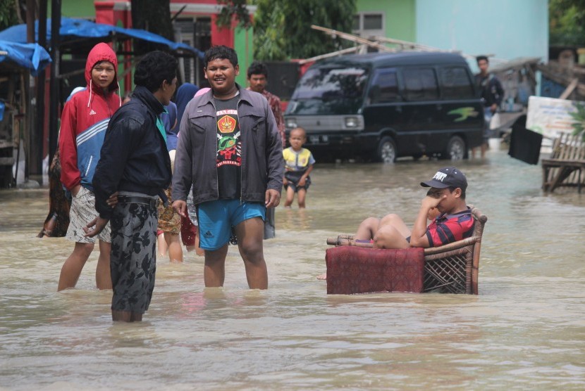 Warga melintasi genangan banjir  di Cirebon, Jawa Barat.