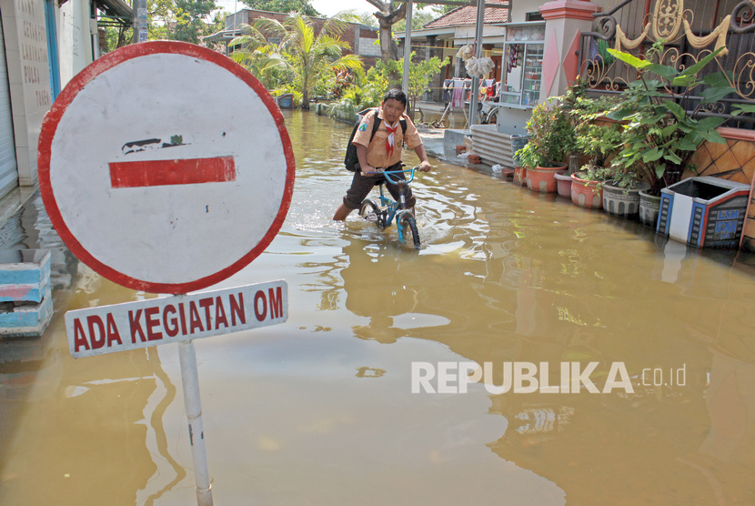 Siswa melintasi banjir yang tak kunjung surut di Desa Kedungbanteng, Tanggulangin, Sidoarjo, Jawa Timur, Jumat (7/2/2020). 