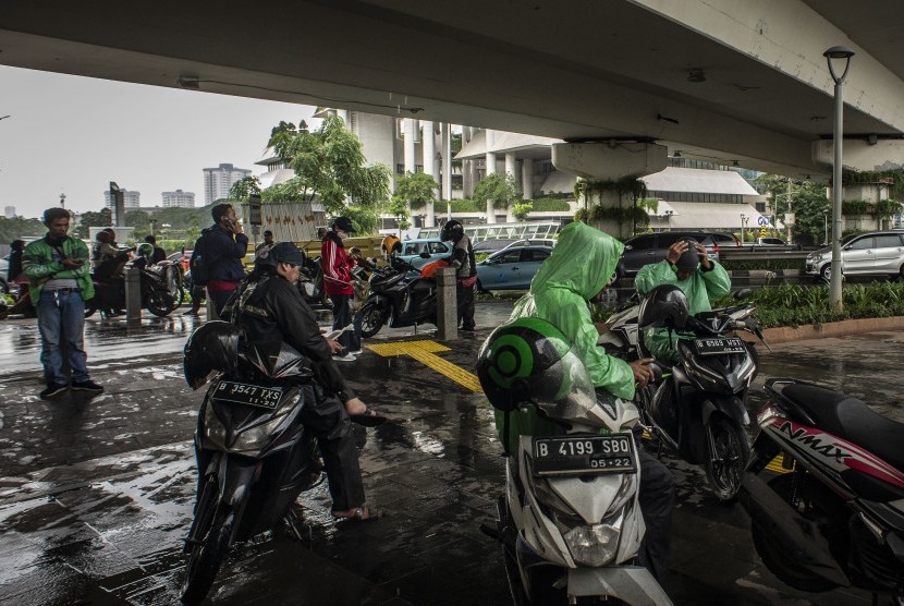 Pengendara sepeda motor berteduh di bawah flyover Jalan KH Mas Mansyur saat hujan di Jakarta, Jumat (7/2/2020).