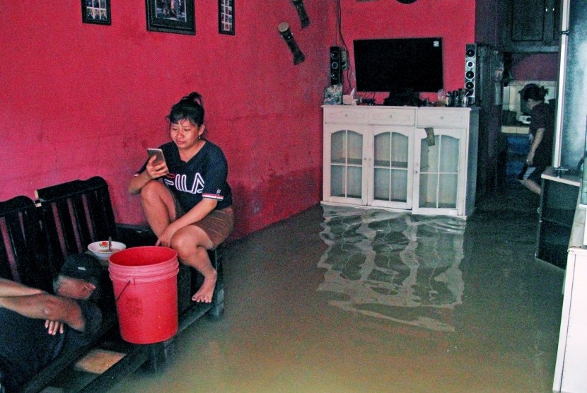 Warga beraktivitas di kawasan permukiman penduduk yang tergenang banjir, di Kampung Petukangan, Cakung, Jakarta, Sabtu (8/2/2020).