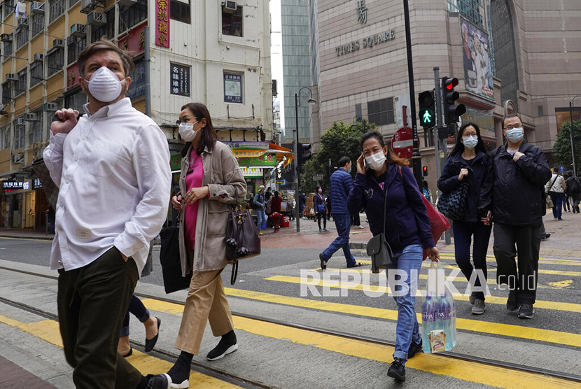 Sejumlah warga mengenakan masker melintasi jalan raya di Hong Kong, Senin (10/2). Ahli virologi dari Inggris menyarankan agar masyarakat mengurangi interaksi fisik, seperti pelukan dan ciuman, untuk menekan penyebaran virus corona tipe baru, Covid-19.