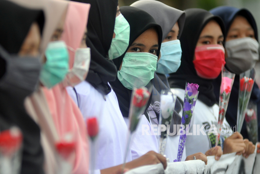 Sejumlah mahasiswi memegang bunga mawar dan menggunakan masker sambil memperlihatkan spanduk kampanye Anti Kekerasan Seksual Terhadap Perempuan, di Padang, Sumatera Barat, Ahad (16/2/2020). 