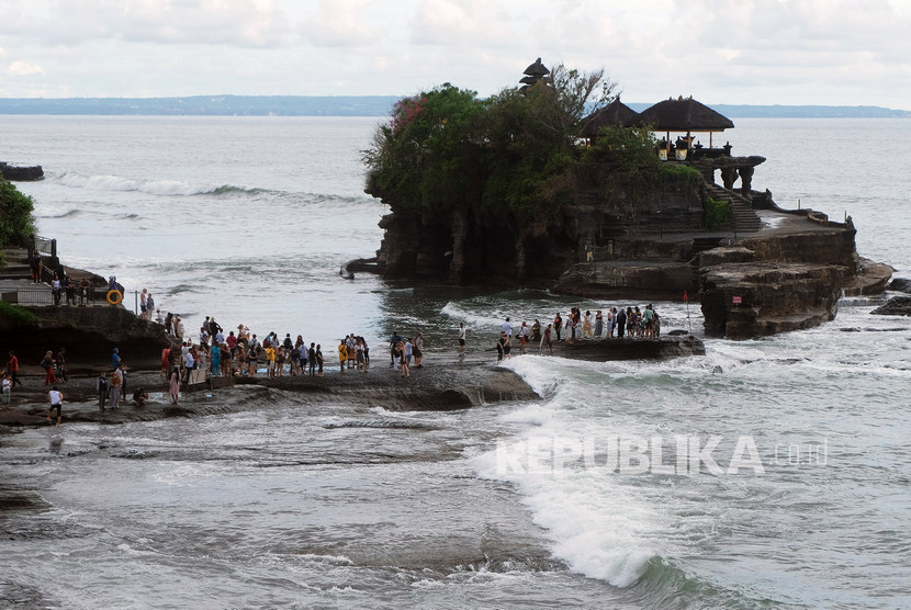 Wisatawan beraktivitas di Pantai Tanah Lot, Tabanan, Bali. Pulau Bali menjadi salah satu kawasan wisata yang terdampak akibat larangan masuknya turis China. Pemerintah memberikan paket insentif untuk menyelamatkan sektor pariwisata.
