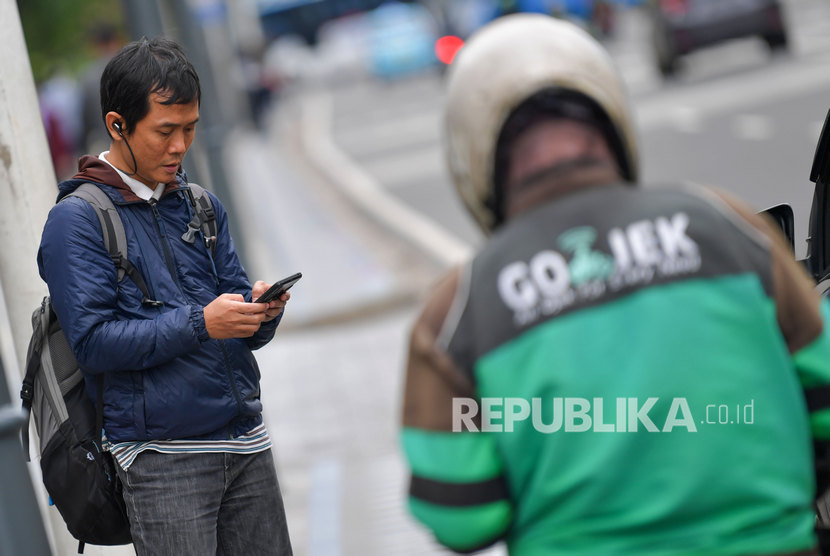 Seorang calon penumpang menanti pengemudi ojek online di Jalan Thamrin, Jakarta, Senin (17/2/2020). 