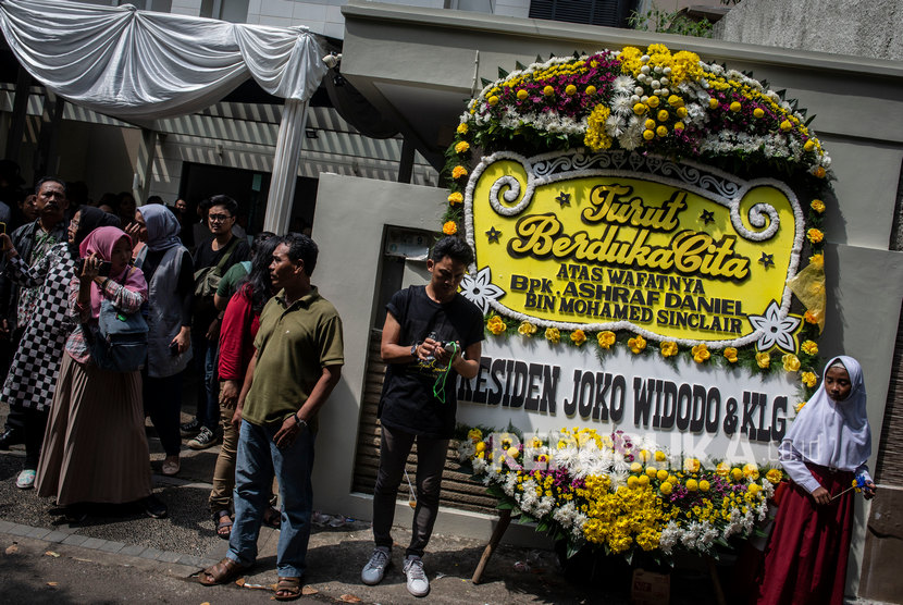Pelayat beraktivitas di dekat karang bunga ucapan belasungkawa atas wafatnya aktor Ashraf Sinclair di rumah duka di kawasan Pejaten Barat, Jakarta, Selasa (18/2/2020).