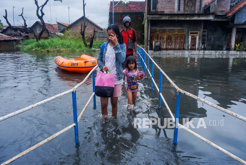 Warga berjalan melewati banjir di Tirto, Pekalongan, Jawa Tengah, Kamis (20/2/2020).