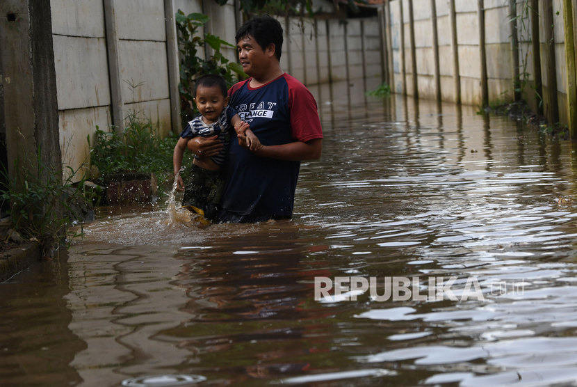 Warga menyusuri jalan perkampungan yang tergenang banjir luapan air Sungai Ciliwung di Cawang, Jakarta, Kamis (20/2/2020). Pada Senin (24/2/2020), warga di bantaran Kali Ciliwung kembali diminta waspada banjir.