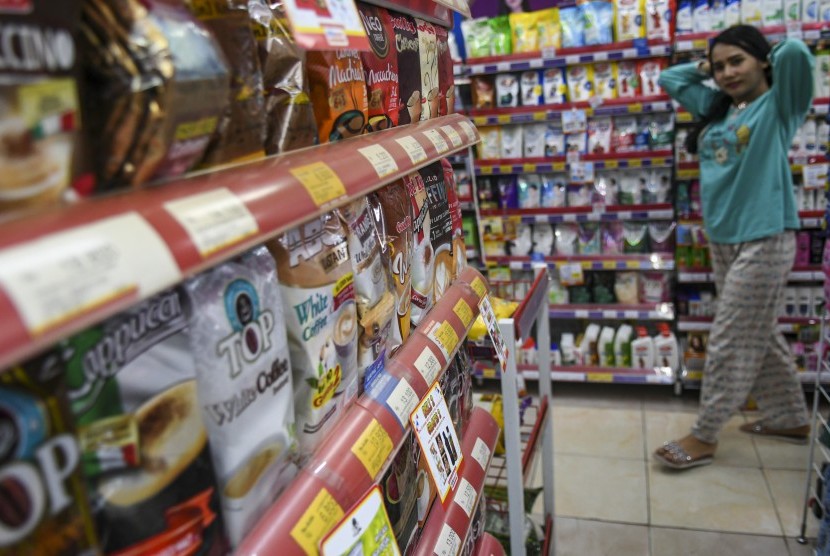 Calon pembeli melintas di depan rak penyimpanan minuman kemasan kecil di salah satu gerai Alfamart, (ilustrasi).