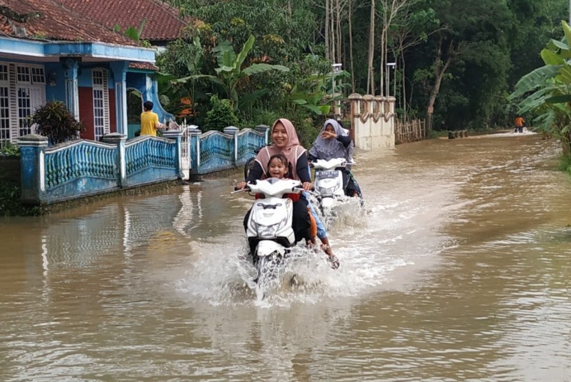 Sejumlah kendaraan memaksa melintas di jalanan yang terendam banjir di Desa Tanjungsari, Kecamatan Sukaresik, Kabupaten Tasikmalaya, Ahad (23/2). 