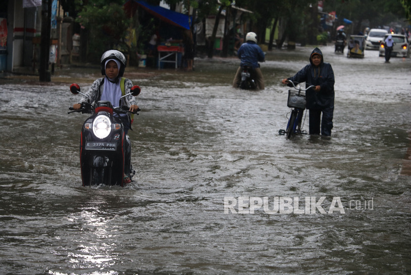 Warga melintasi banjir di jalan Yos Sudarso, Indramayu, Jawa Barat, Senin (24/2/2020).