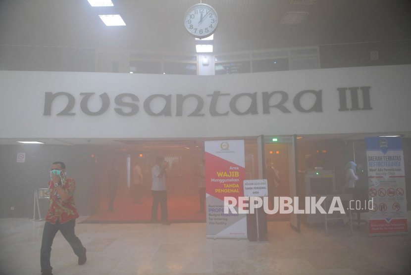 Karyawan berjalan keluar ruangan saat terjadi kepulan asap putih di Gedung Nusantara III, Kompleks Parlemen, Senayan, Jakarta, Senin (24/2/2020).