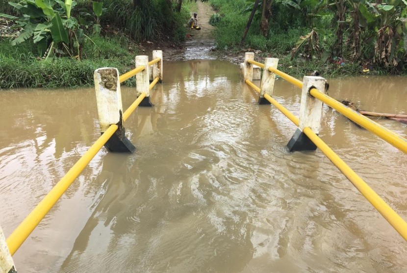 Jembatan penghubung permukiman dengan Tempat Pemakaman Bukan Umum (TBPU) Ranca Bulan di Kampung Koceak, Keranggan, Setu, Tangerang Selatan (Tangsel) terendam luapan Kali Cisadane, Senin (24/2).