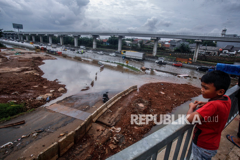 Seorang anak melihat ruas tol Jatibening yang terendam banjir di Bekasi, Jawa Barat, Selasa (25/2). Mengenai penyebab banjir yang melanda sejumlah titik di wilayah Bekasi pada Selasa (25/2), pemprov Jabar mengatakan salah satunya disebabkan oleh curah hujan yang cukup tinggi. 