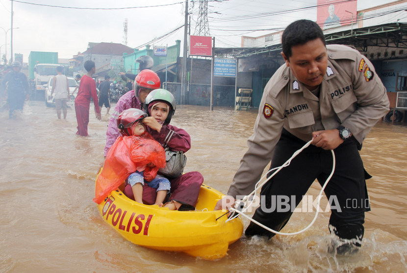Anggota polisi membantu evakuasi warga saat banjir yang terjadi di Desa Telaga Asih, Cikarang Barat, Kabupaten Bekasi, Jawa Barat, Selasa, (25/2/2020). 