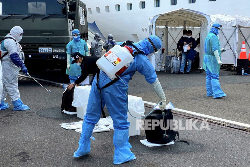 Petugas kesehatan menyemprotkan cairan disinfektan kepada WNI ABK Diamond Princess dan barang bawaan saat turun dari kapal di Yokohama, Jepang, Ahad (2/3/3030).