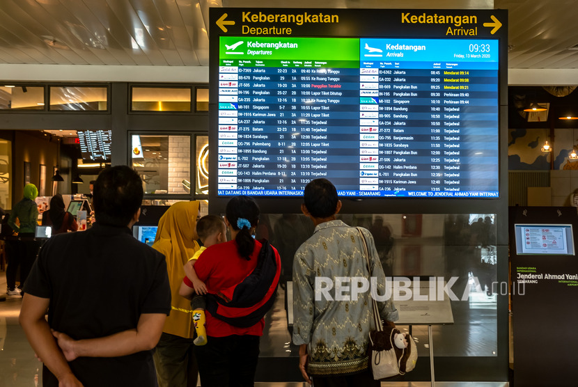 Sejumlah penumpang mengamati layar informasi kedatangan dan keberangkatan pesawat di Bandara Internasional Jenderal Ahmad Yani Semarang, Jawa Tengah, Jumat (13/3/2020).