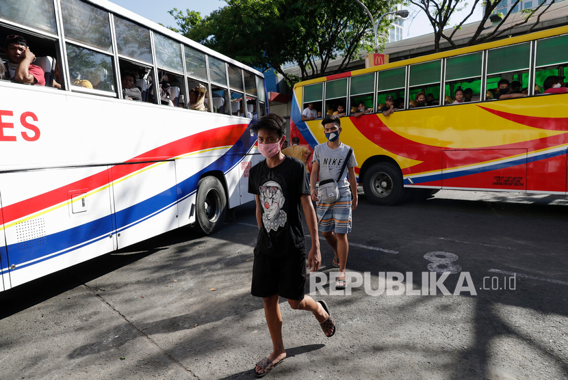 Pria yang mengenakan topeng pelindung berjalan di terminal bus Cubao di Manila, Filipina, Jumat, 13 Maret 2020.(AP/Aaron Favila)