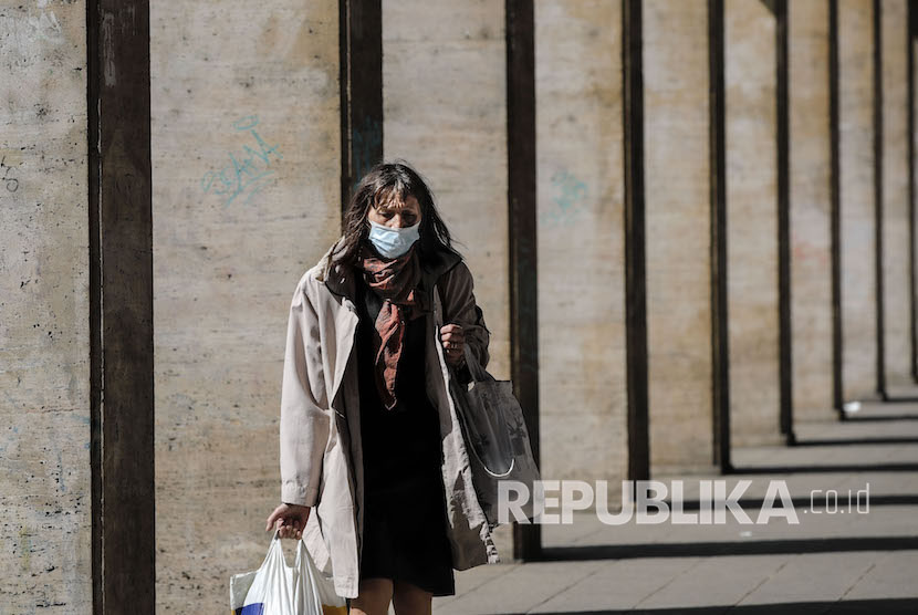 Seorang wanita mengenakan maskersaat membawa kantung belanja saat diberlakukan lockdown untuk mengurangi penyebaran virus Corona di Bucharest, Romania, Selasa, (7/4).