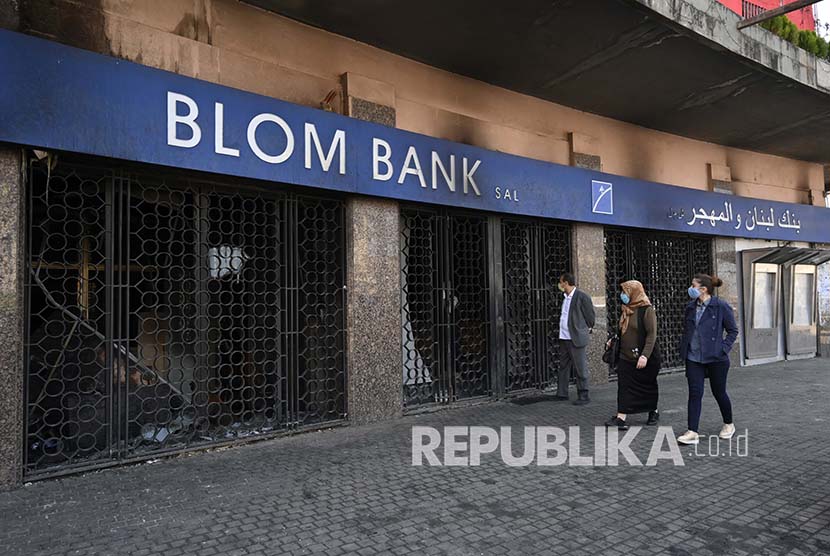 Sejumlah orang berjalan di depan bank yang rusak akibat dibakar pengunjuk rasa anti-pemerintah di Al Nour Square di utara kota Tripoli, Lebanon, Selasa (28/4). Setidaknya 30 pengunjuk rasa terluka dan satu tewas dalam bentrokan semalam antara pengunjuk rasa dan tentara Lebanon. Beberapa bank dirusak dan setidaknya satu dibakar. Asosiasi Bank-bank Lebanon menyatakan semua bank di Tripoli tutup mulai 28 April hingga kondisi keamanan pulih. Bank telah menjadi sasaran serangan serius dalam kerusuhan di tengah krisis keuangan yang sedang berlangsung.  EPA-EFE/WAEL HAMZEH.
