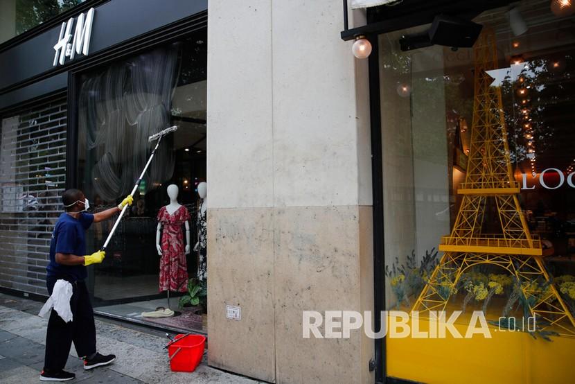 Seorang pekerja membersihkan jendela toko di jalan Champs Elysée, Paris, Senin (11/5). 