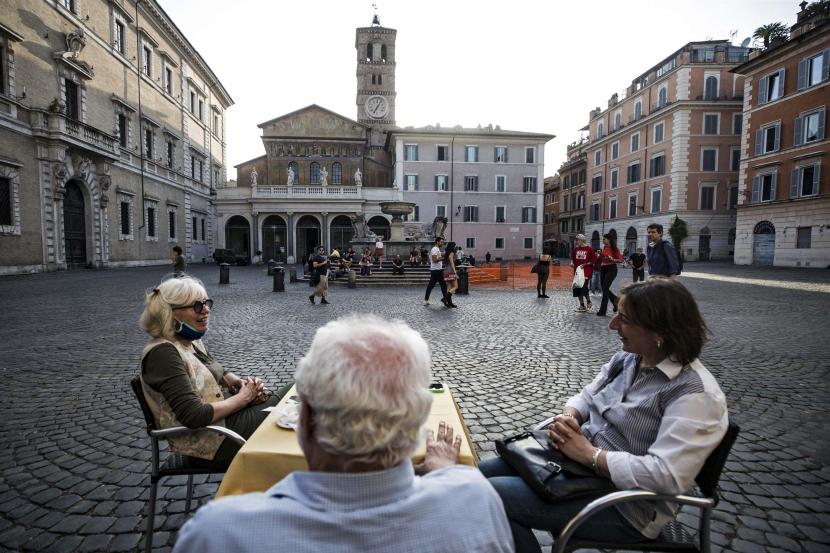 Sejumlah orang menikmati makanan di sebuah restoran di distrik Trastevere selama fase dua masa pemulihan pandemi Covid-19, Roma, Italia, Senin (18/5). Italia secara bertahap mencabut kebijakan lockdown yang diterapkan untuk membendung penyebaran COVID-19.