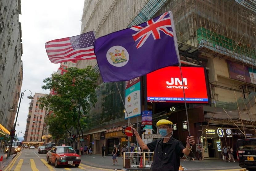 Seorang peserta aksi mengibarkan bendera Amerika Serikat dan Hong Kong di Causeway Bay, Hong Kong. Menurut pemberitahuan pemerintah AS yang diposting pekan lalu, barang yang dibuat di Hong Kong untuk diekspor ke AS perlu diberi label sebagai buatan China setelah 25 September. Ilustrasi.
