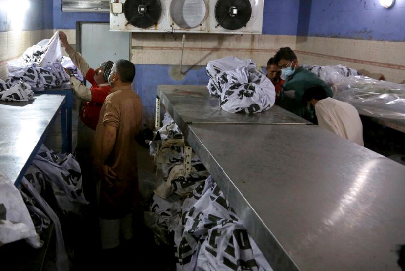 Warga berusaha mengidentifikasi bagian tubuh saudara mereka yang menjadi korban pesawat jatuh di Karachi, Pakistan, Ahad (24/5).