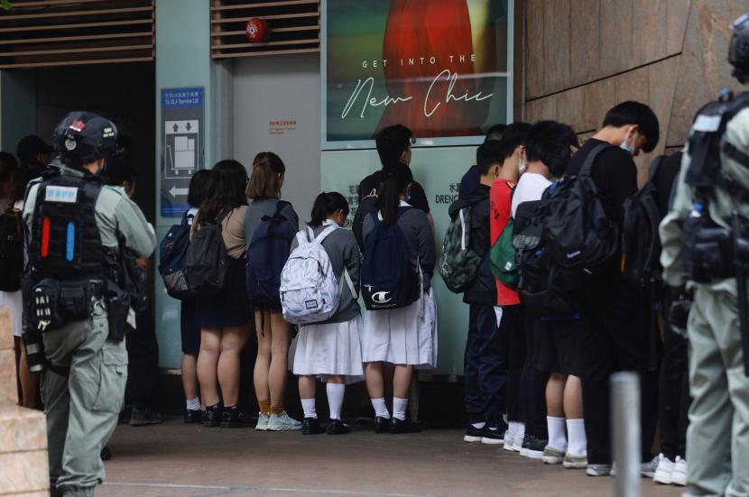 Para pemrotes yang ditahan dan siswa-siswa sekolah menengah menghadapi tembok sambil menunggu polisi merekam identitas mereka di Mongkok, Hong Kong, Rabu (27/5). Ribuan pengunjuk rasa meneriakkan slogan-slogan pro-demokrasi dan menghina polisi di Hong Kong sebelum para pembuat undang-undang Rabu kemudian membahas RUU mengkriminalisasi penyalahgunaan lagu kebangsaan Cina di kota semi-otonom.  Foto AP / Kin Cheung