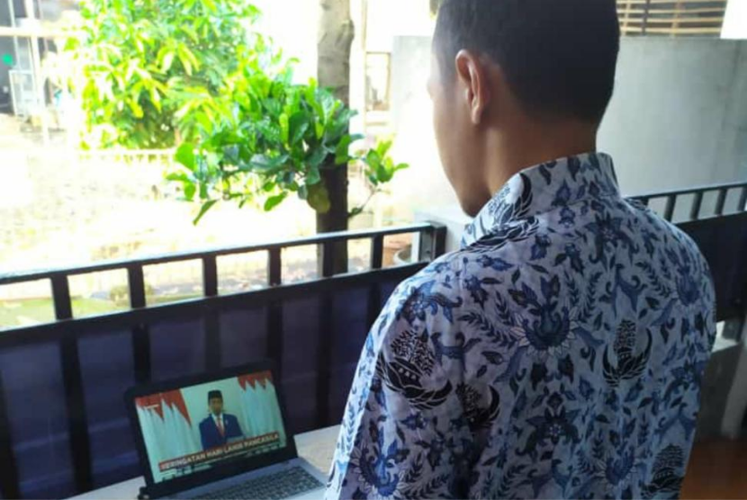 Seorang PNS mengikuti kegiatan Peringatan Hari Lahir Pancasila secara virtual dengan tetap menggunakan baju Korpri.