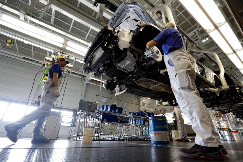 Pekerja menyelesaikan rakitan mobil di pabrik Volkswagen di Wolfsburg, Jerman. Output industri Jerman mencatat penurunan tertajam pada April