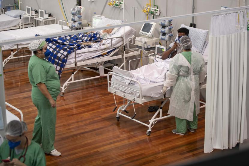 Pasien COVID-19 menerima perawatan ketika mereka berbaring di ranjang di rumah sakit lapangan yang dibangun di dalam gym di Santo Andre, di Sao Paulo, Brasil, Selasa (9/6).  