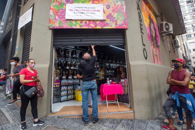 Seorang pria membuka tokonya yang berada di sebuah pusat pertokoan di Sao Paulo, Brasil, Rabu (10/6).