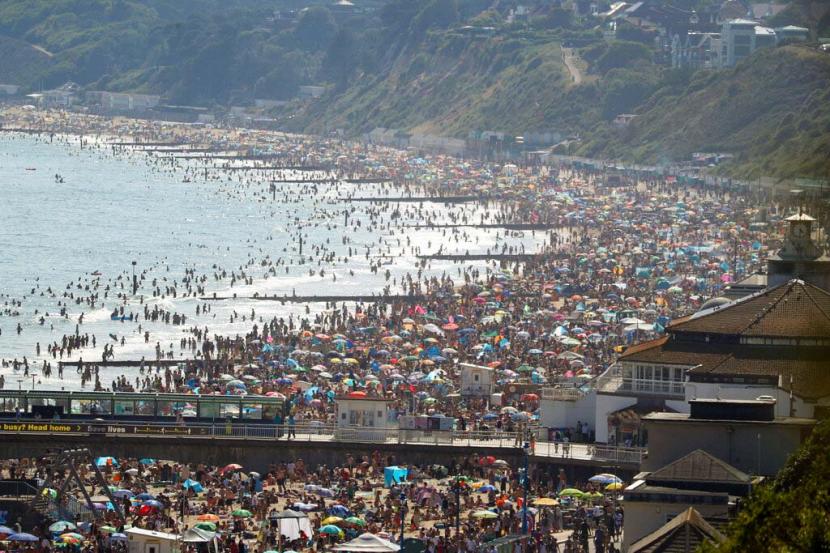 Orang-orang memadati  pantai pada musim terpanas tahun ini mencapai 32,6 derajat celcius, setelah masa pelonggaran pembatasan sosial akibat coronavirus, di Bournemouth, Inggris, Rabu (24/6). 