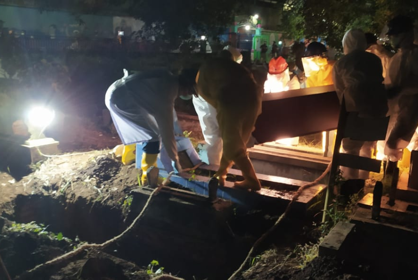 Petugas melakukan prosesi pemakaman jenazah Covid-19 di Kota Malang.