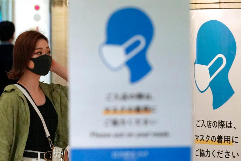 Perempuan melintas di balik imbauan menggunakan masker di Tokyo, Jepang, Jumat (3/7). Survei menunjukkan, warga Jepang banyak yang tak puas dengan cara pemerintah menangani pandemi Covid-19. 