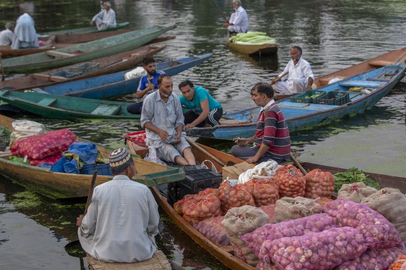 Pemimpin Muslim Prihatin dengan Situasi Kashmir. Seorang pria Kashmir, Benar, menegosiasikan tarif saat ia bersiap untuk membayar uang setelah membeli sayuran dari pedagang di pasar sayur terapung di Danau Dal di Srinagar, Kashmir yang dikuasai India.