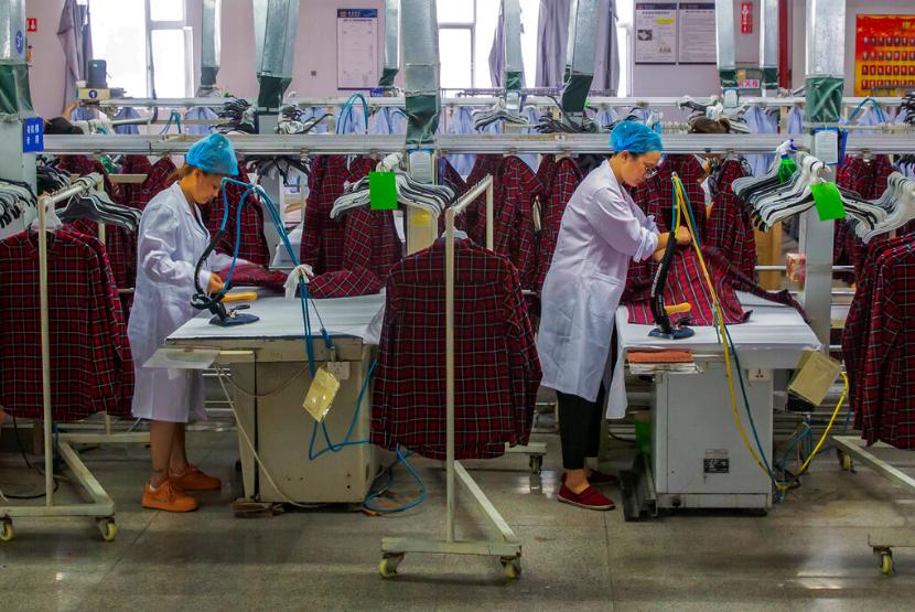 Pekerja menyetrika seragam produksi pabrik pakaian di Kota Hai