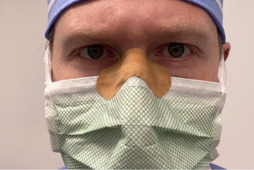 Dokter bedah Daniel Heiferman memasang plester di di bagian pangkal hidung agar kacamatanya tak berembun saat memakai masker.