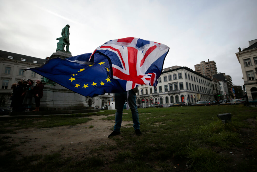 Seorang warga mengibarkan bendera Inggris dan Uni Eropa