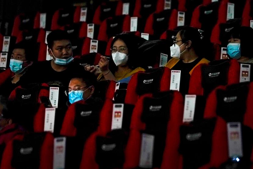 Penonton memakai masker menikmati film di sebuah bioskop di Beijing, China, Kamis (25/2).