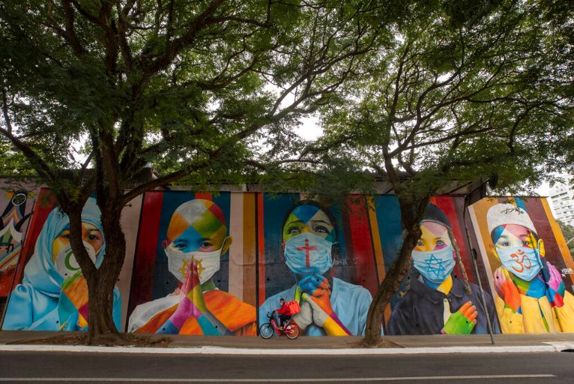 Pesepeda melewati grafiti di Sao Paulo, Brasil, Jumat (7/5). Pemerintah di Sao Paulo, Brasil memberlakukan perpanjangan aturan pembatasan selama dua pekan mendatang.