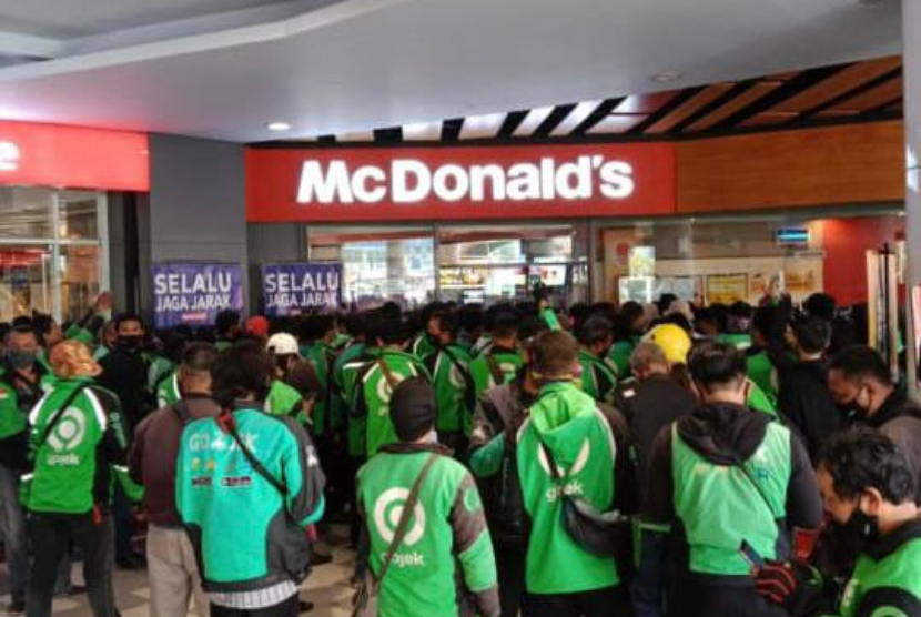 Pengemudi ojek online berkerumun menunggu pesanan BTS Meal dari aplikasi pemesanan makanan Gofood dan Grabfood di Mal Graha Cijantung, Jakarta Timur, Rabu (9/6).